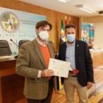 Sebastián Sevilla Díaz, vocal de la Junta Rectora de la Demarcación de Extremadura del CICCP, recibe la insignia en nombre de Pedro A. Lancho Baños, por parte de Andrés Licerán González, Segundo Teniente de Alcalde y Concejal de Fomento, Infraestructuras, Servicios Públicos, Seguridad y Recursos Humanos del Ayuntamiento de Cáceres